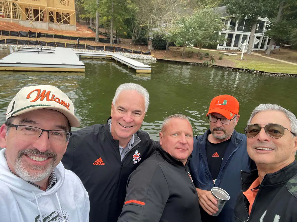 A woman holding a door for a man carrying a bag on his shoulder