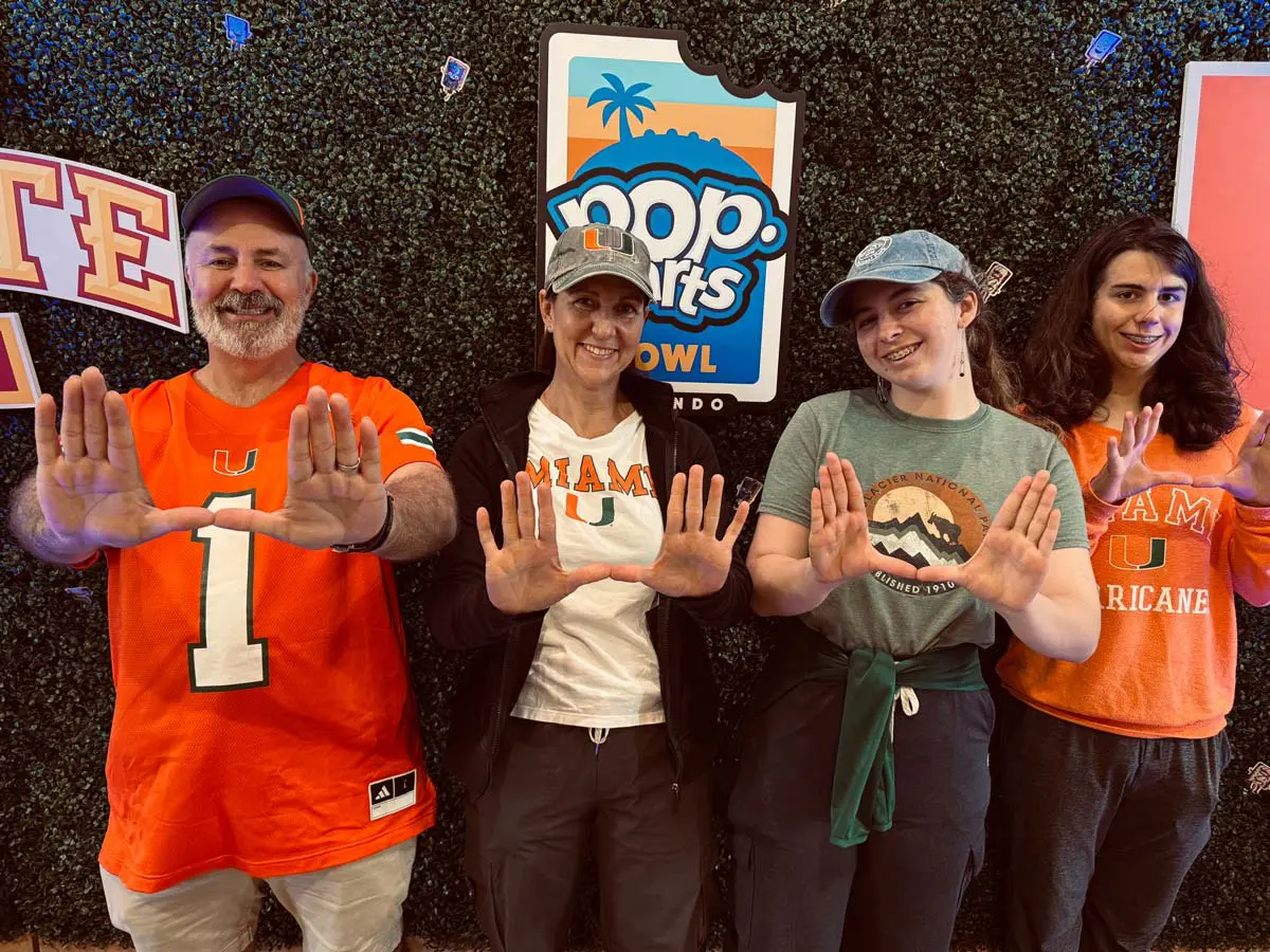 A woman holding a door for a man carrying a bag on his shoulder