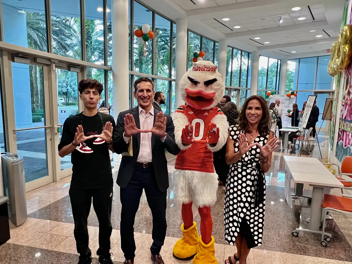 A woman holding a door for a man carrying a bag on his shoulder