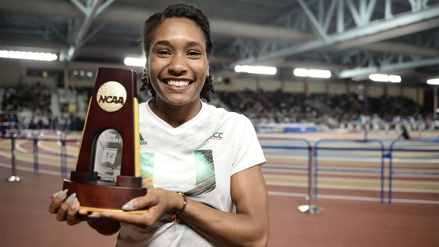 Female track athlete holding trophy and smiling