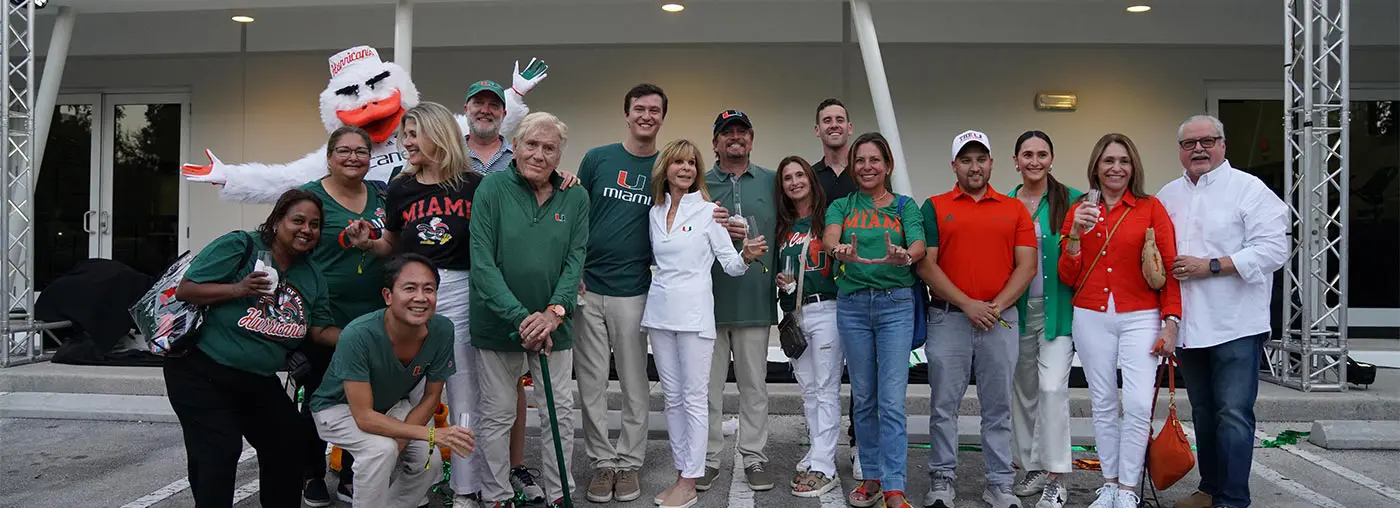 a group of people posing with miami mascot