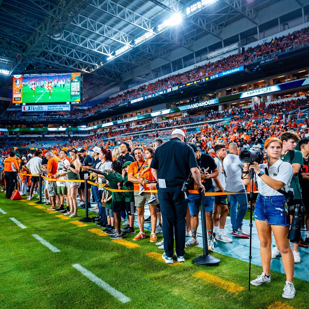 Miami Football fans and photographer on field