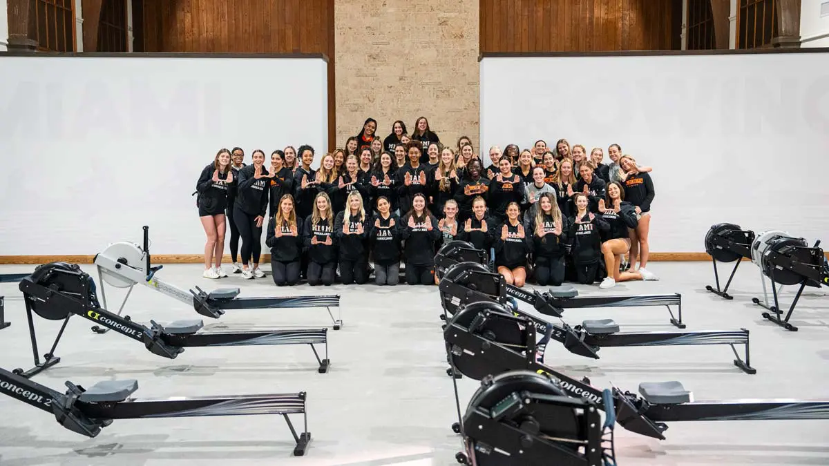 athletes posing behind rowing machines